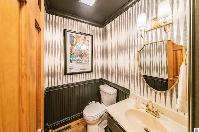 bathroom featuring toilet, vanity, and ornamental molding