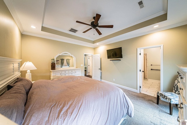 carpeted bedroom featuring ceiling fan, ensuite bath, crown molding, and a tray ceiling