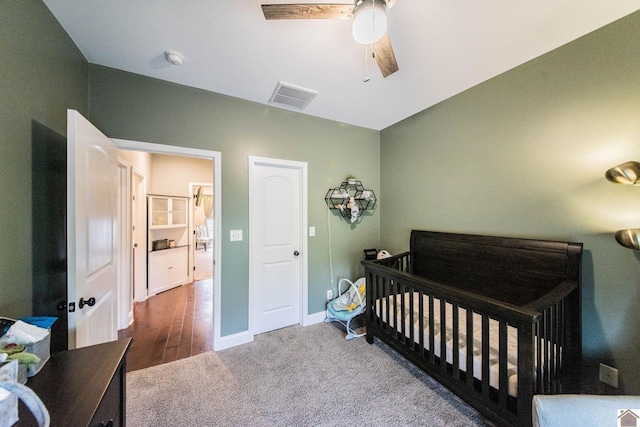 bedroom with ceiling fan, wood-type flooring, and a nursery area