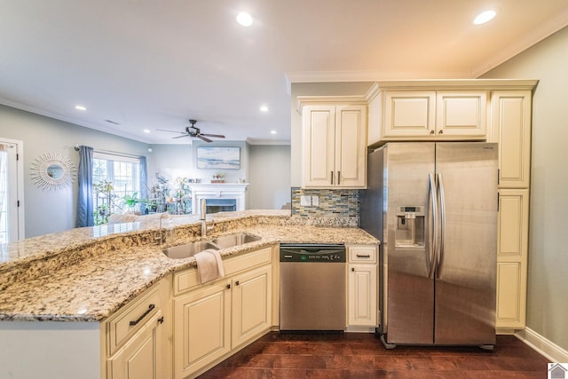 kitchen with light stone counters, stainless steel appliances, sink, cream cabinets, and dark hardwood / wood-style floors