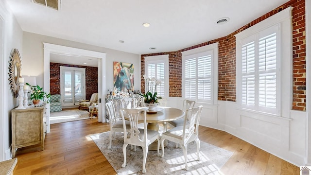 333 N 7th St Unit B, Paducah, KY 42001 - dining area with a wainscoted wall, visible vents, brick wall, and light wood-type flooring