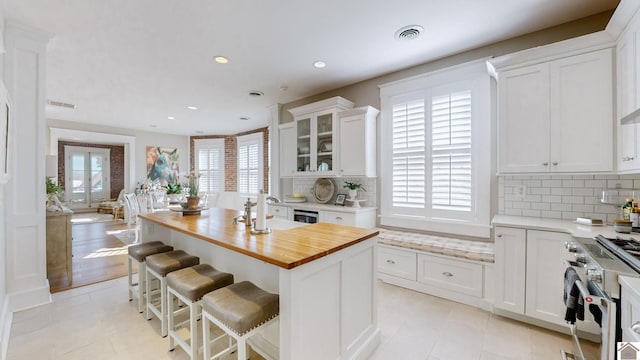 333 N 7th St Unit B, Paducah, KY 42001 - kitchen featuring high end stainless steel range oven, white cabinetry, decorative backsplash, visible vents, and butcher block countertops