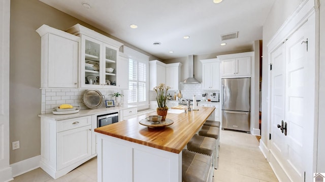 333 N 7th St Unit B, Paducah, KY 42001 - kitchen featuring wood counters, stainless steel fridge, wall chimney range hood, white cabinets, and visible vents