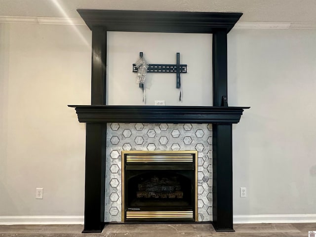 interior details featuring a tile fireplace, wood-type flooring, and crown molding