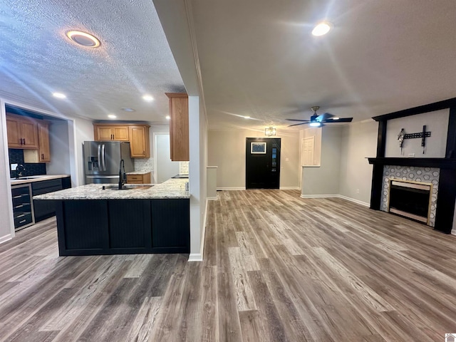 kitchen with a textured ceiling, wood-type flooring, stainless steel refrigerator with ice dispenser, and a tile fireplace