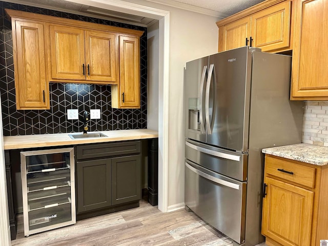 kitchen featuring stainless steel refrigerator with ice dispenser, light wood-type flooring, backsplash, sink, and wine cooler