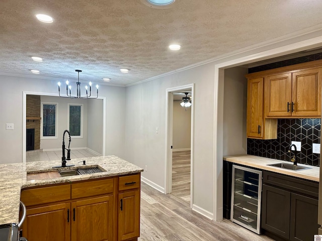 kitchen with light wood-type flooring, sink, beverage cooler, and tasteful backsplash