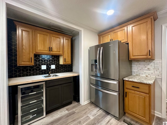 kitchen featuring sink, wine cooler, stainless steel fridge with ice dispenser, crown molding, and light hardwood / wood-style floors