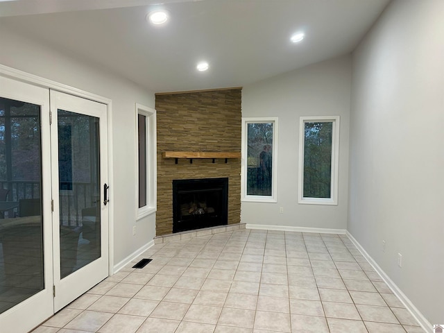 unfurnished living room featuring a fireplace, lofted ceiling, and light tile patterned flooring