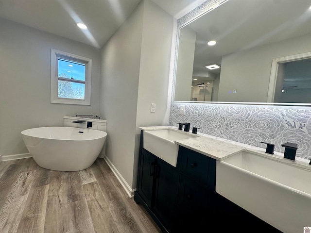 bathroom with plus walk in shower, hardwood / wood-style floors, vanity, and tasteful backsplash