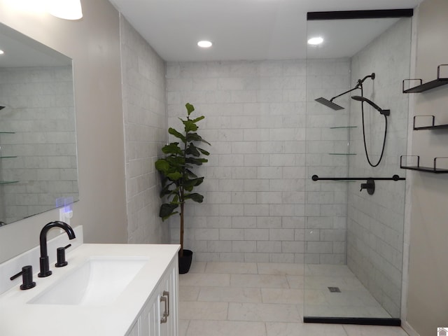 bathroom with tile patterned floors, vanity, and a tile shower