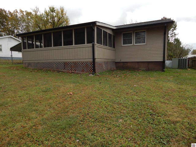 rear view of house with central air condition unit and a lawn