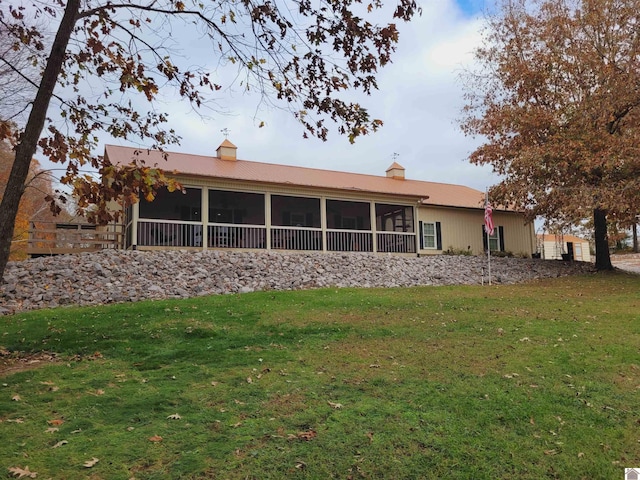 back of house featuring a lawn and a sunroom