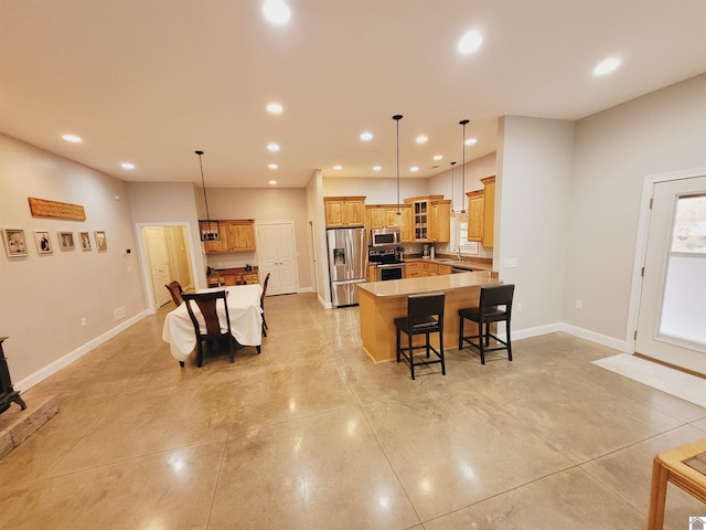 kitchen with sink, hanging light fixtures, stainless steel appliances, a kitchen bar, and a kitchen island