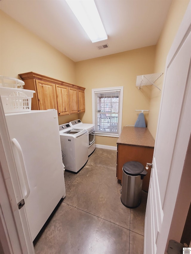 clothes washing area with washing machine and dryer and cabinets