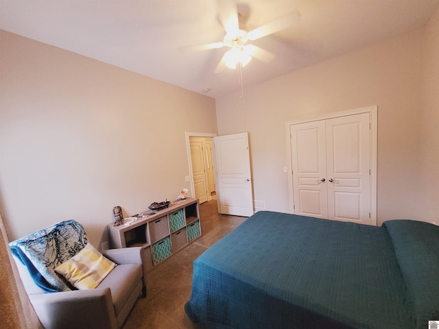 bedroom with dark tile patterned flooring, ceiling fan, and a closet