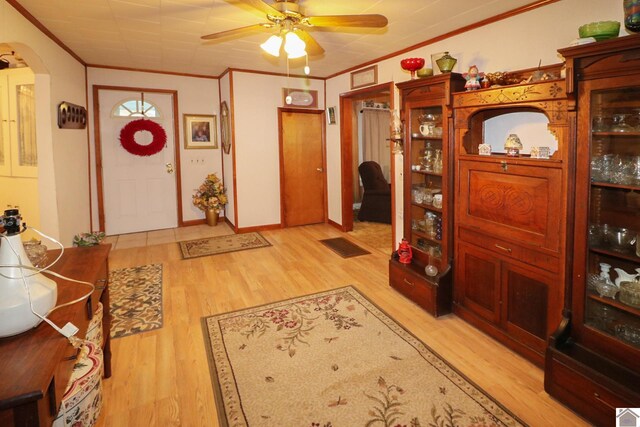 entryway with ceiling fan, crown molding, and light hardwood / wood-style floors