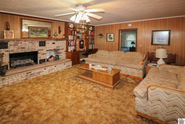 carpeted living room with a fireplace, ornamental molding, ceiling fan, and wooden walls