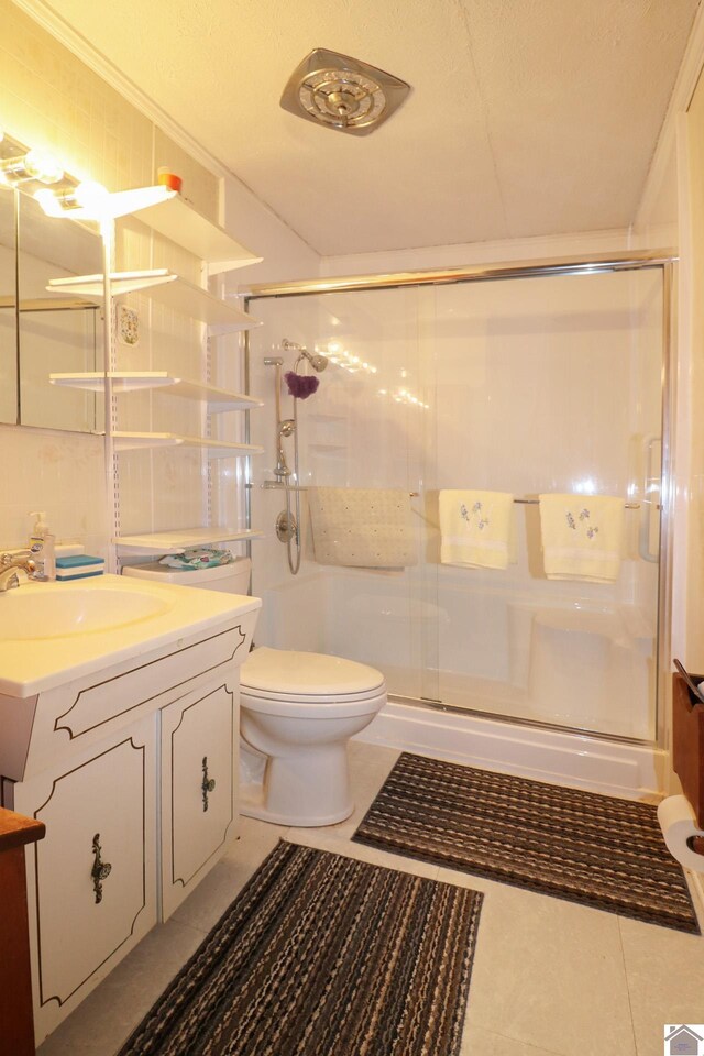 bathroom with tile patterned floors, vanity, an enclosed shower, and toilet