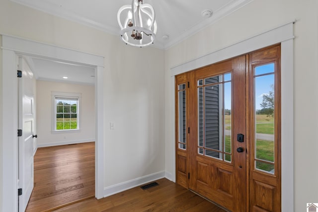 entrance foyer featuring a chandelier, ornamental molding, and dark wood-type flooring