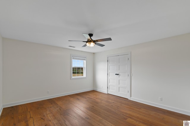 unfurnished bedroom featuring a closet, hardwood / wood-style flooring, and ceiling fan