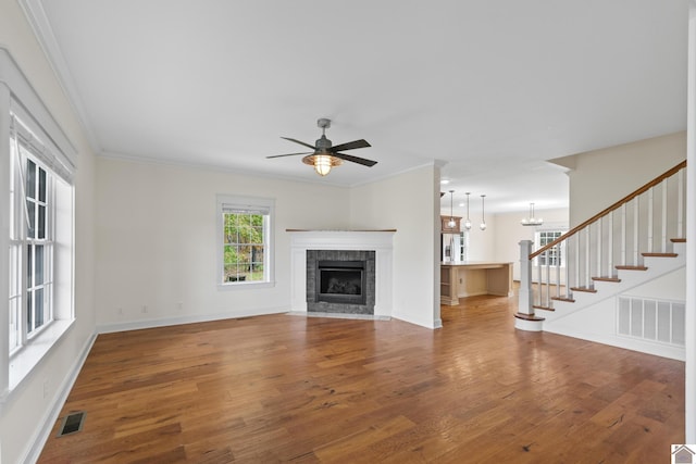 unfurnished living room with ceiling fan with notable chandelier, hardwood / wood-style flooring, and ornamental molding