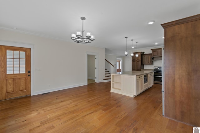 kitchen with crown molding, light hardwood / wood-style flooring, a center island, stainless steel stove, and hanging light fixtures