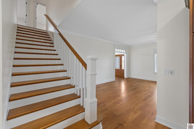 stairs with wood-type flooring and crown molding