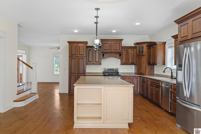 kitchen with hardwood / wood-style floors, a center island, crown molding, sink, and stainless steel appliances