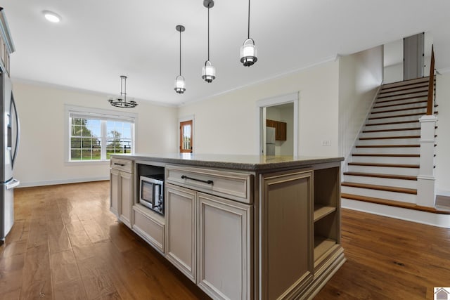 kitchen featuring a center island, light stone countertops, appliances with stainless steel finishes, decorative light fixtures, and dark hardwood / wood-style flooring