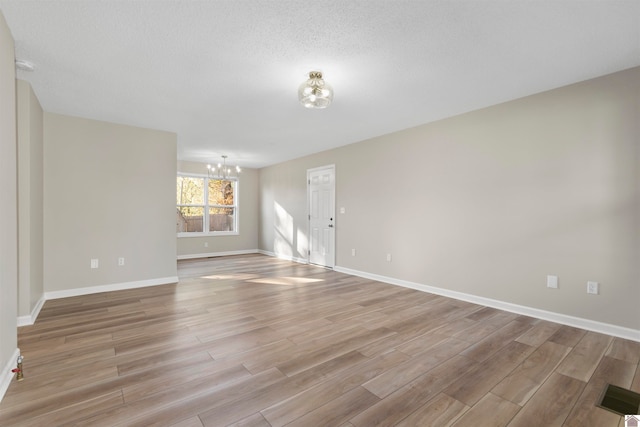 spare room with light hardwood / wood-style flooring and a chandelier