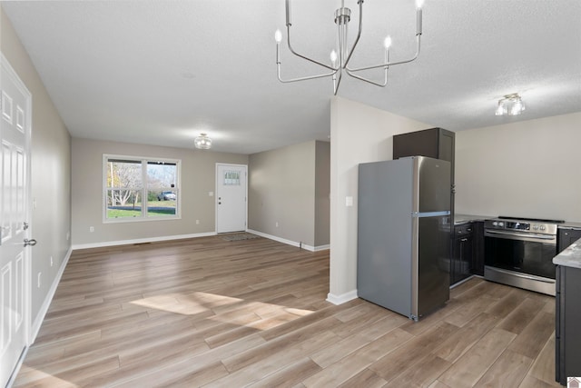 kitchen featuring a textured ceiling, a notable chandelier, light hardwood / wood-style floors, and stainless steel appliances