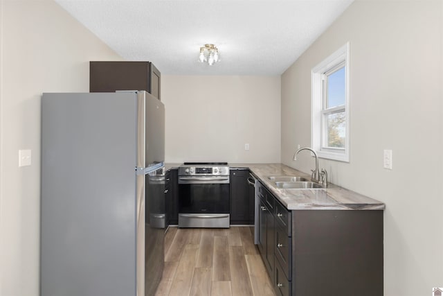 kitchen featuring sink, stainless steel appliances, a textured ceiling, and light wood-type flooring