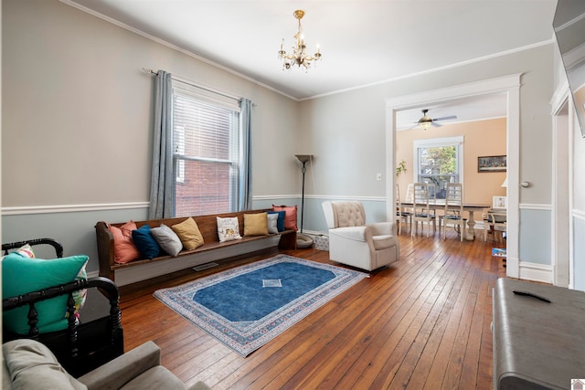 living room with hardwood / wood-style flooring, ceiling fan with notable chandelier, and crown molding