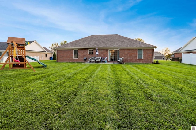 rear view of house featuring a playground and a yard