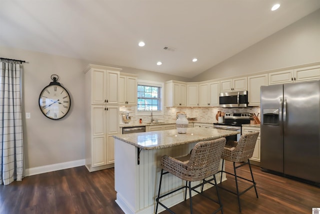 kitchen with a center island, dark wood-type flooring, sink, vaulted ceiling, and stainless steel appliances