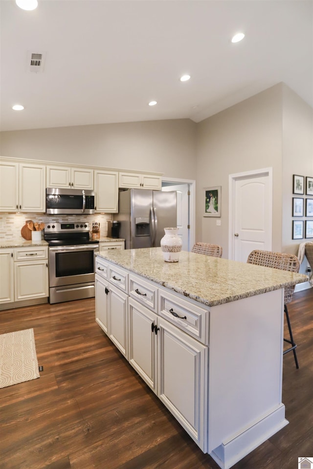 kitchen featuring a center island, lofted ceiling, stainless steel appliances, and dark wood-type flooring