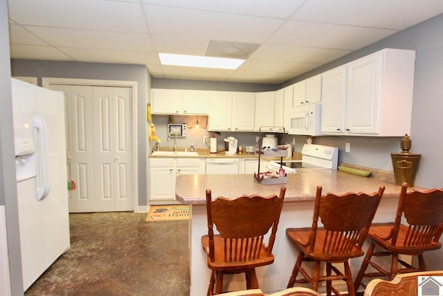 kitchen featuring a drop ceiling, white cabinetry, white appliances, and a breakfast bar