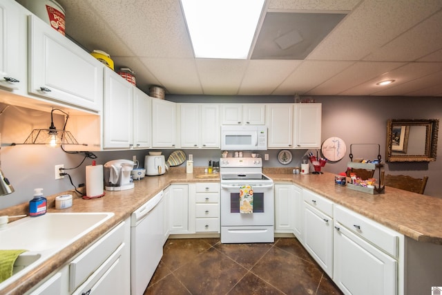 kitchen with sink, a drop ceiling, kitchen peninsula, white appliances, and white cabinets