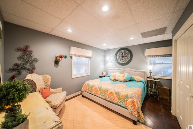 bedroom featuring a drop ceiling and parquet flooring