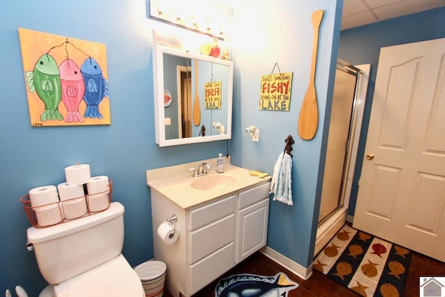 bathroom featuring a drop ceiling, toilet, walk in shower, and vanity