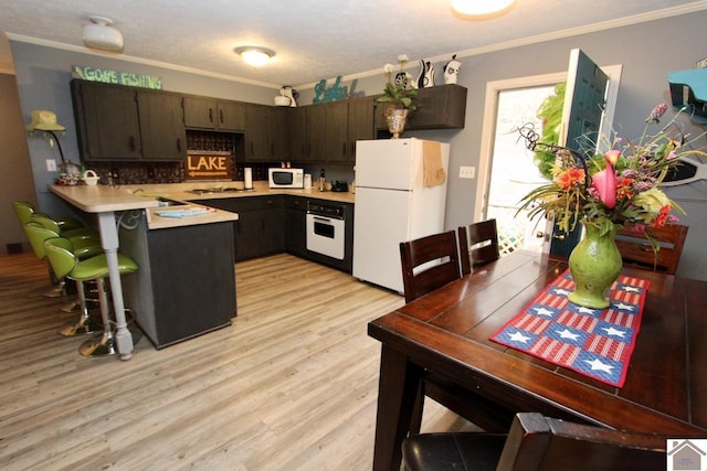 kitchen featuring light hardwood / wood-style floors, crown molding, white appliances, and kitchen peninsula