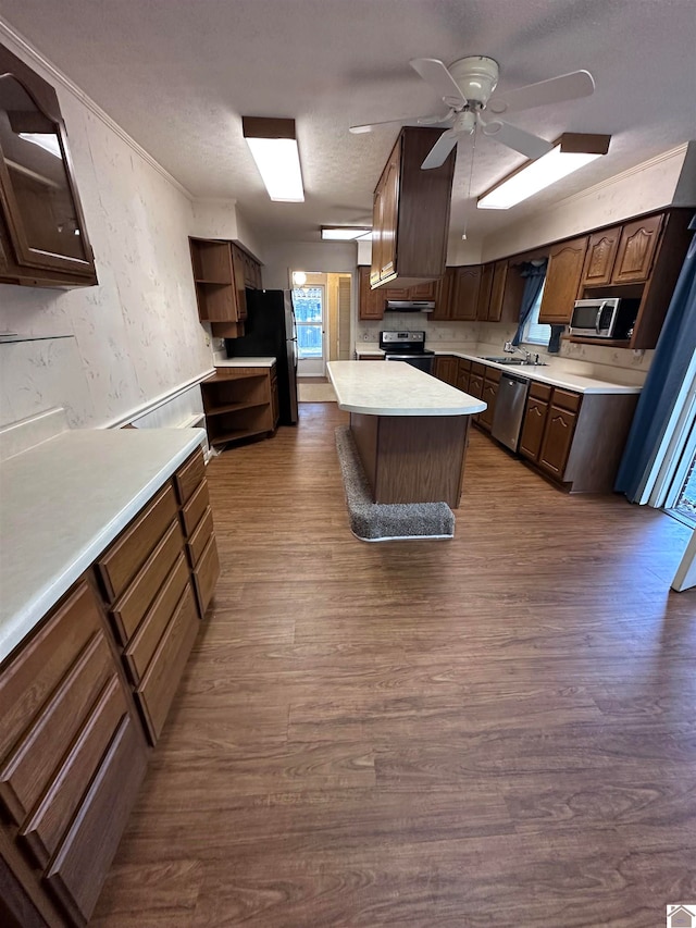 kitchen with ceiling fan, a kitchen island, dark hardwood / wood-style flooring, and appliances with stainless steel finishes