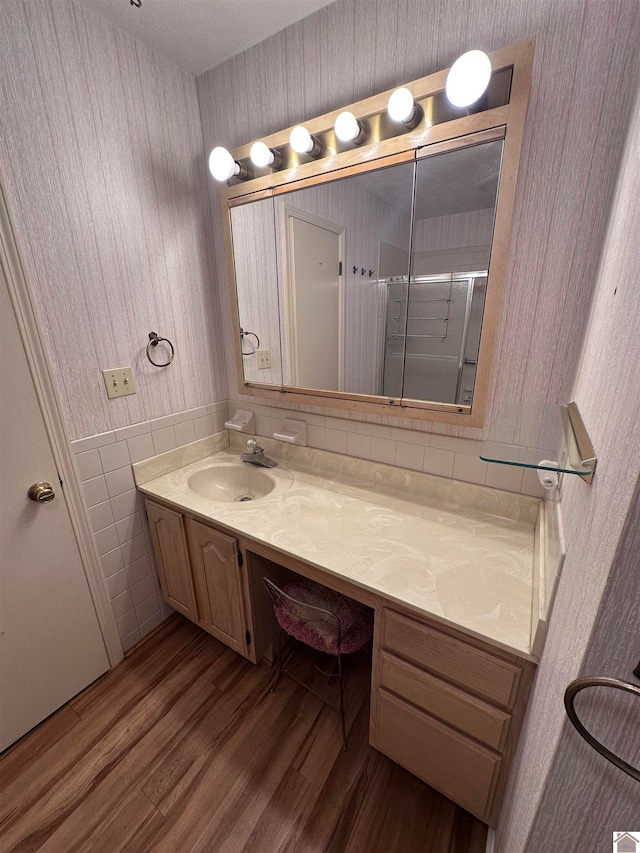 bathroom with walk in shower, vanity, hardwood / wood-style flooring, and tile walls