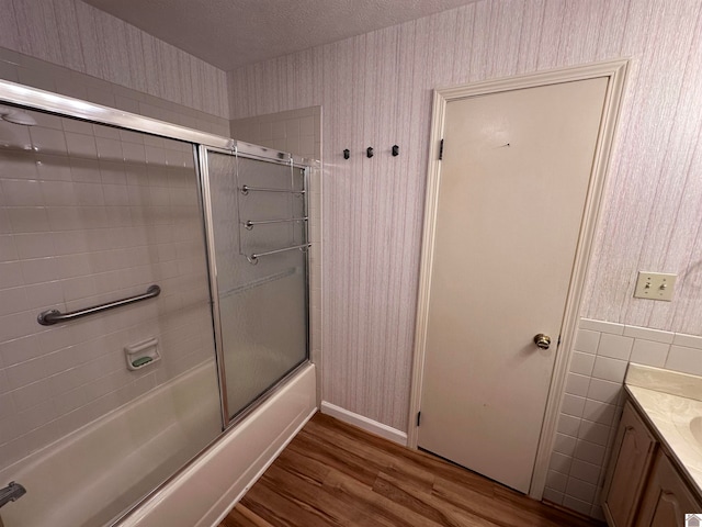 bathroom featuring vanity, enclosed tub / shower combo, a textured ceiling, and hardwood / wood-style flooring