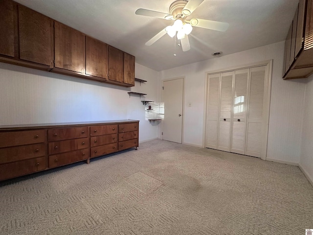 kitchen with ceiling fan, dark brown cabinetry, and light carpet