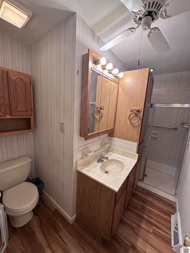 bathroom featuring vanity, a shower with door, ceiling fan, wood-type flooring, and toilet