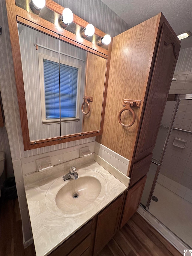 bathroom featuring walk in shower, hardwood / wood-style floors, a textured ceiling, toilet, and vanity