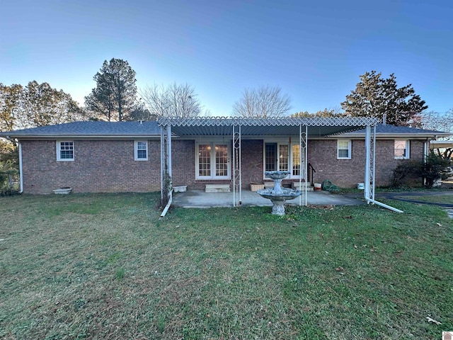 rear view of house featuring a pergola, a patio area, and a lawn