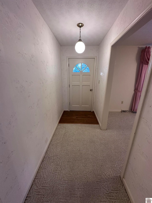 doorway to outside with light colored carpet and a textured ceiling